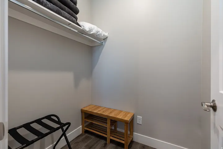 Walk in closet with dark wood-style floors