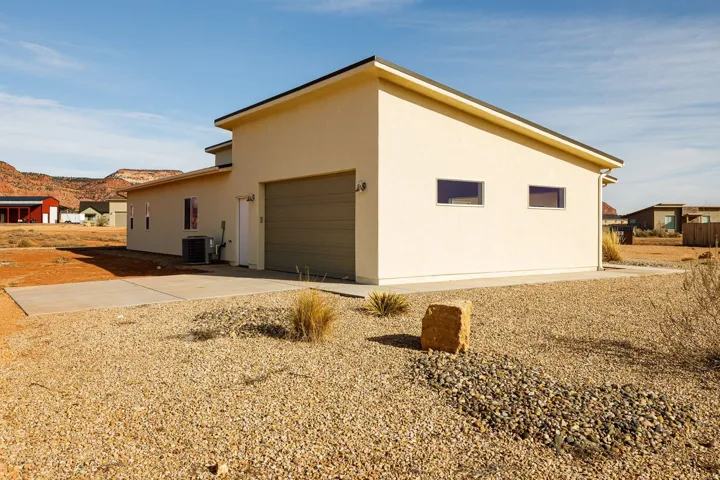 View of side of home featuring stucco siding, driveway, a garage, and a mountain view