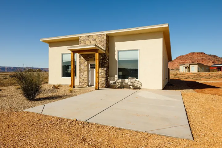 View of front of property with stone siding, stucco siding, and a patio