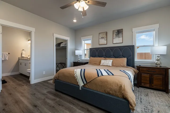 Bedroom with a spacious closet, wood finished floors, ceiling fan, recessed lighting, and ensuite bathroom