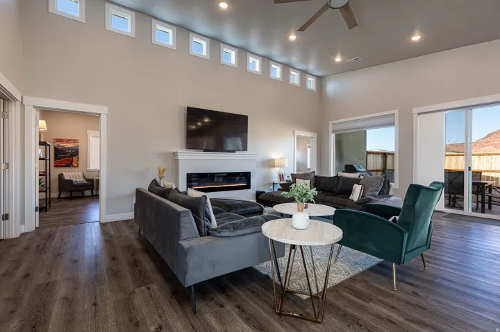 Living area with a glass covered fireplace, a ceiling fan, a high ceiling, recessed lighting, and dark wood-style flooring