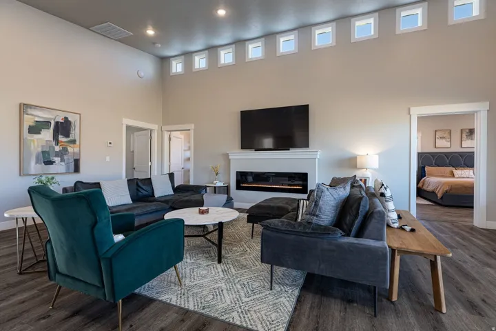 Living room with a high ceiling, wood finished floors, a glass covered fireplace, and recessed lighting