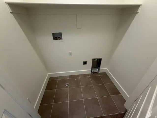 Dedicated utility space featuring neutral wall paint and brown square tile flooring