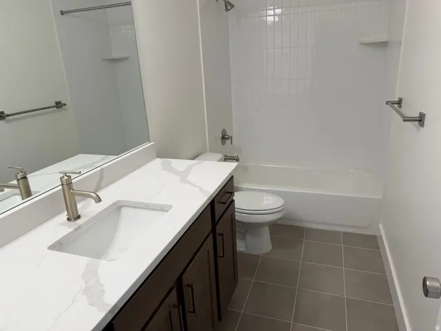 Bathroom featuring a large vanity with a quartz countertop, integrated rectangular sink, and brushed nickel faucet