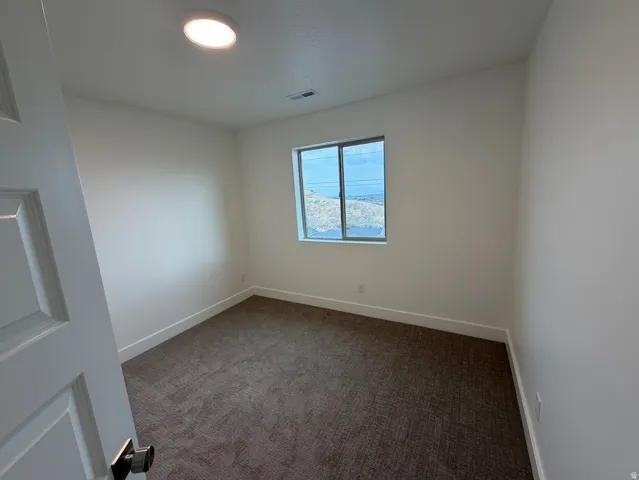 Room featuring neutral-toned walls, recessed ceiling lighting, and dark patterned carpeting