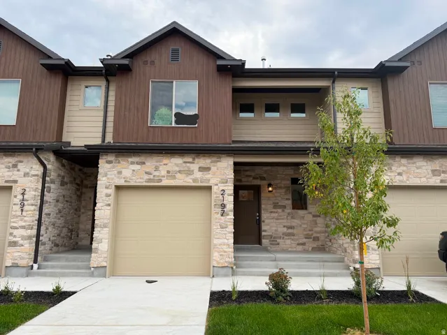 Contemporary facade with stone veneer, horizontal siding, and dark trim