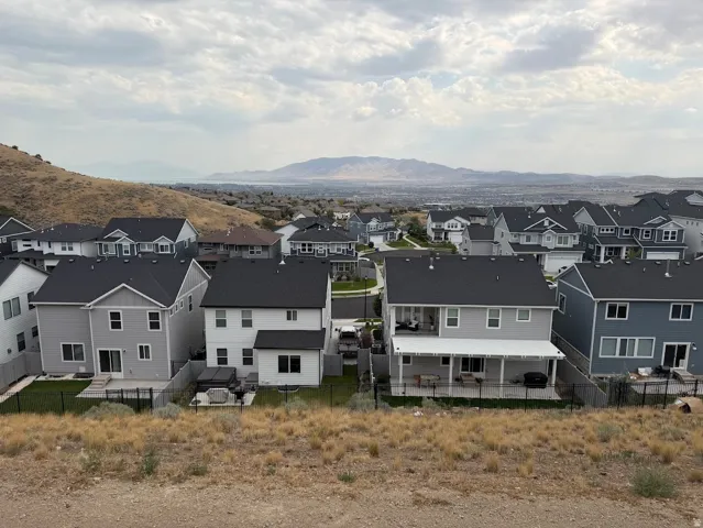 Hillside setting featuring multiple residences with dark roofing, light-toned siding, and fenced rear yards