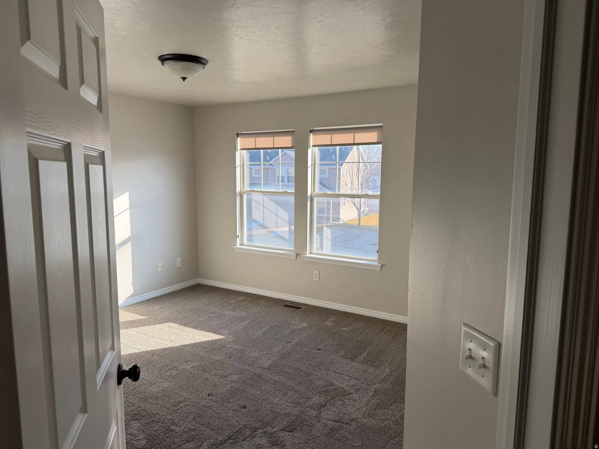 Unfurnished bedroom with a textured ceiling and dark carpet