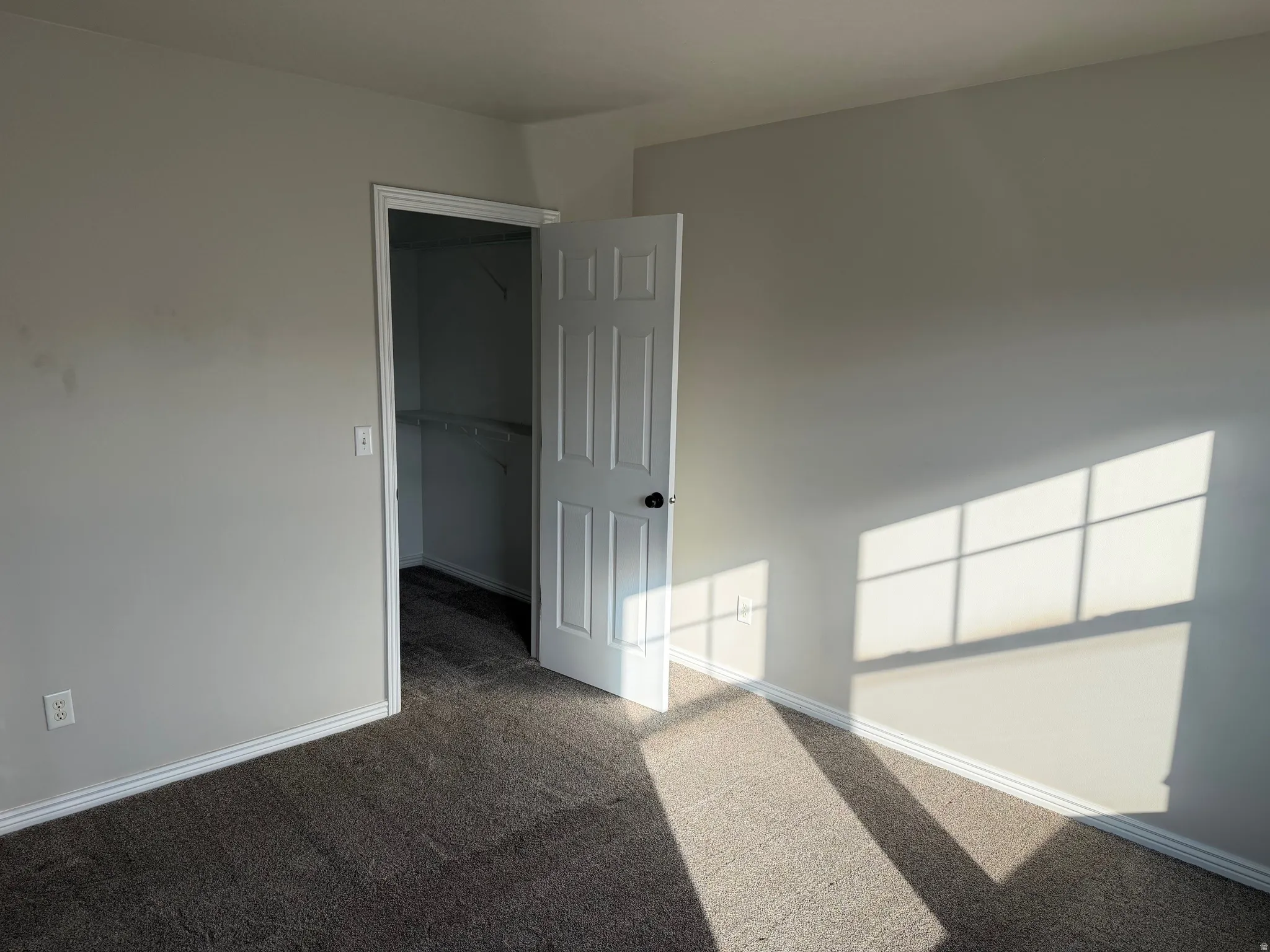 Carpeted spare room featuring baseboards