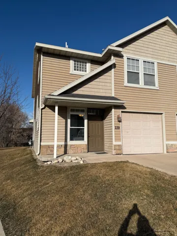 View of front of home with a front yard, a garage, covered porch, and driveway