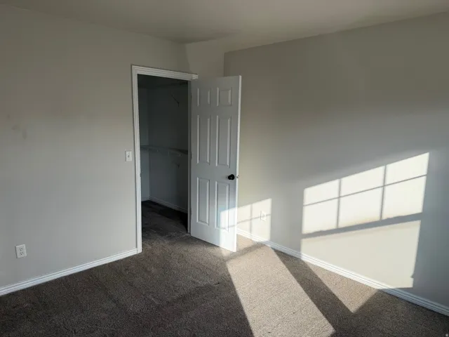 Carpeted spare room featuring baseboards