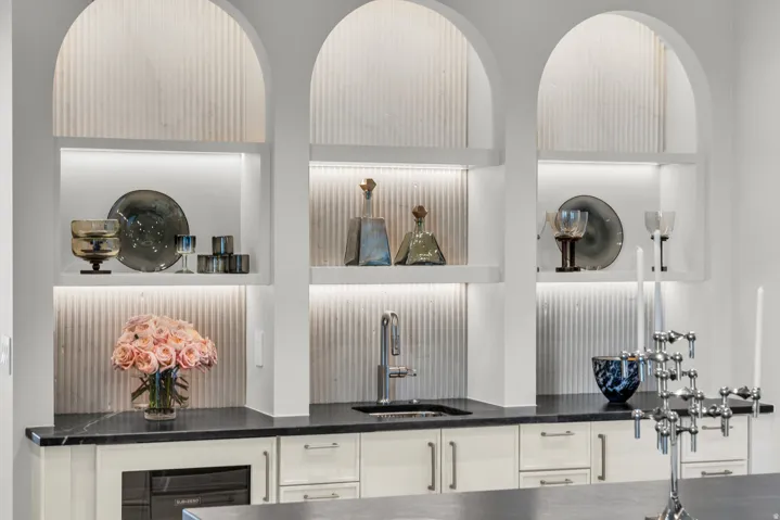Detailed view of open shelves, beverage cooler, white cabinets, and dark stone counters