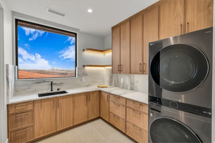 Laundry room with cabinet space, stacked washer / dryer, recessed lighting, and light tile patterned flooring