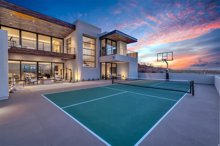 View of tennis court featuring a patio and a balcony