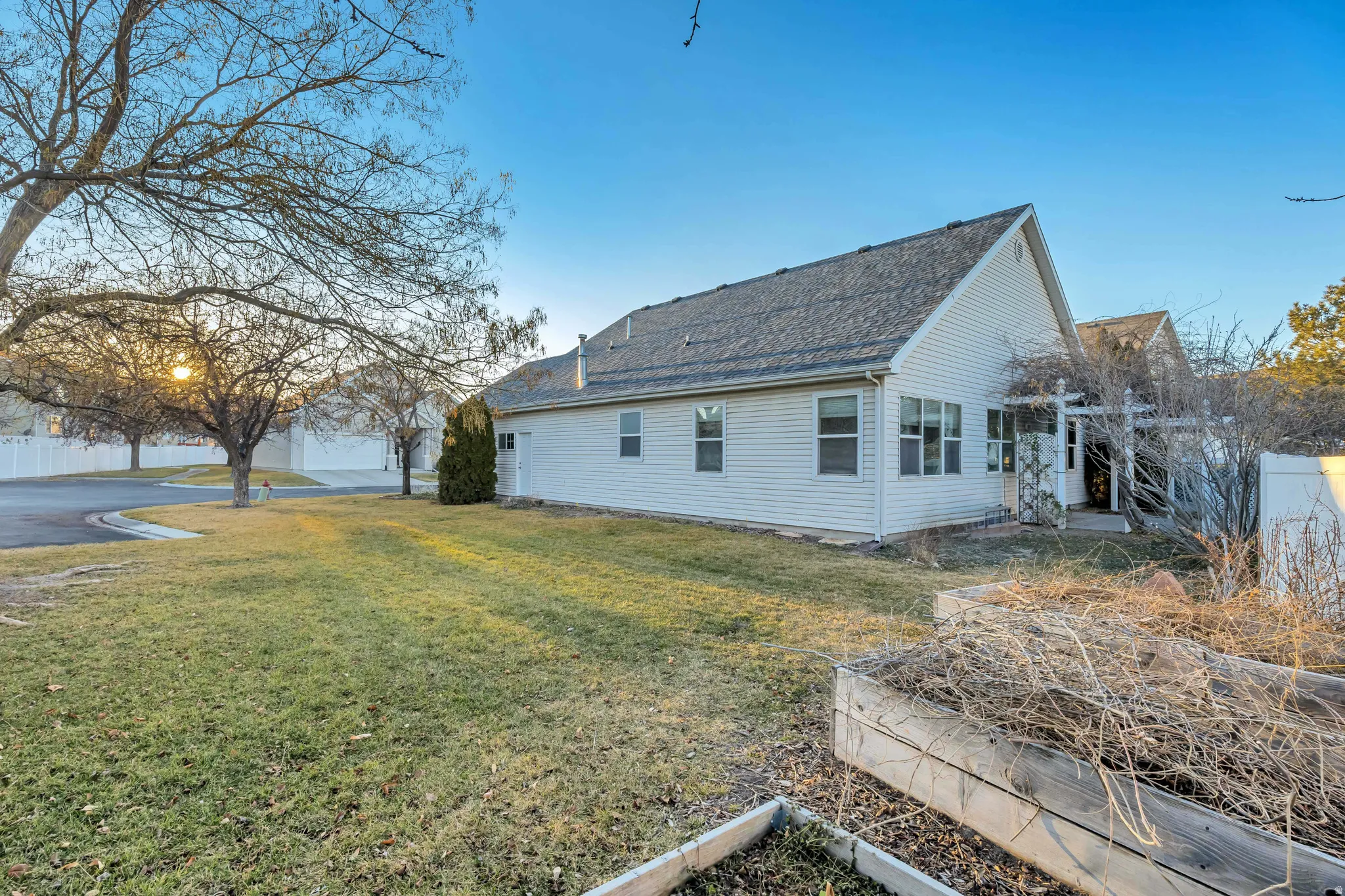 View of side of property featuring a yard, a shingled roof, and a garden