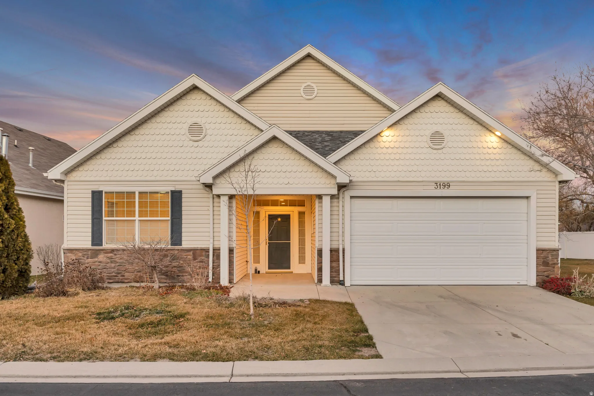 View of front of home featuring stone siding, driveway, a garage, and a lawn