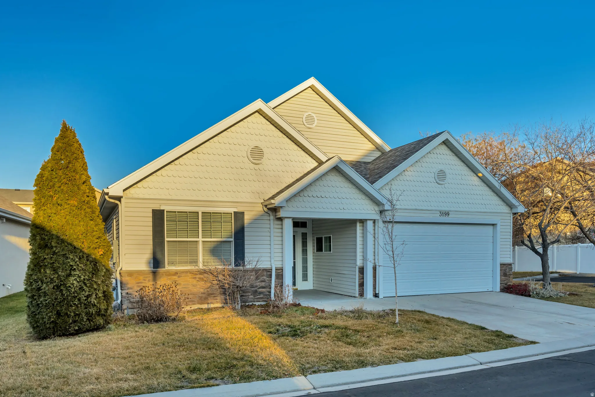 View of front of house featuring an attached garage, a front yard, concrete driveway, and stone siding
