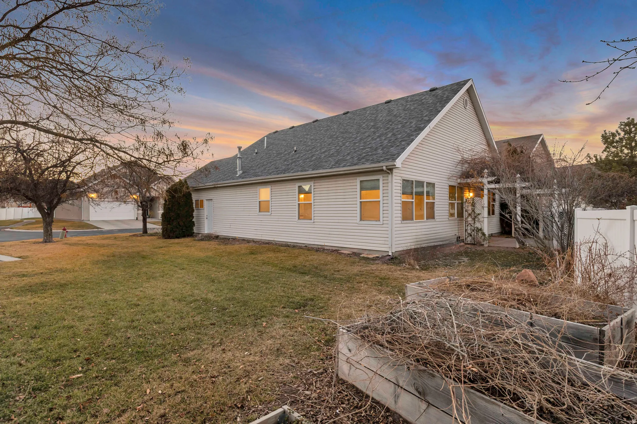 Property exterior at dusk with a shingled roof and a garden