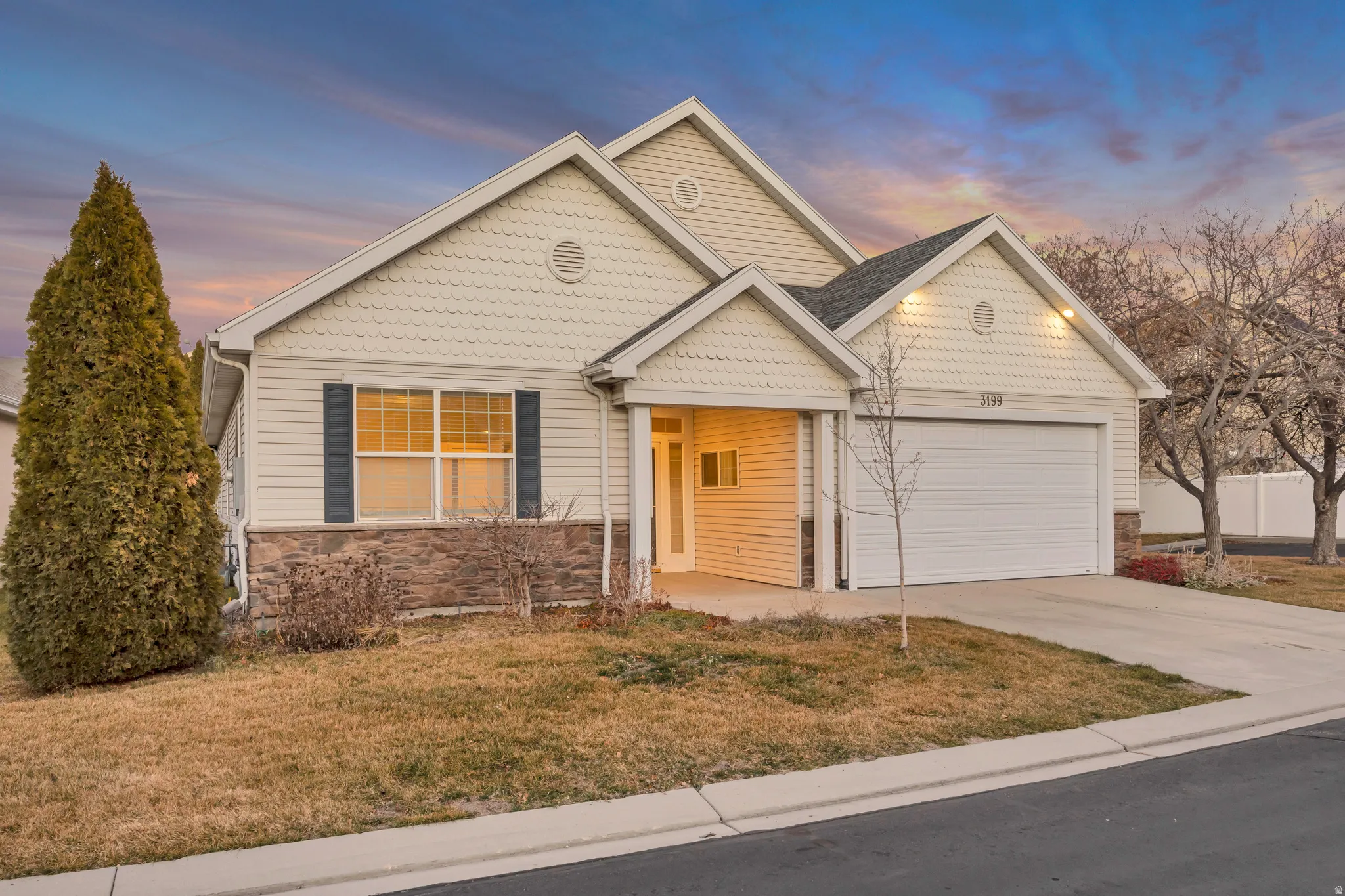 View of front of house featuring stone siding, a front yard, concrete driveway, and an attached garage