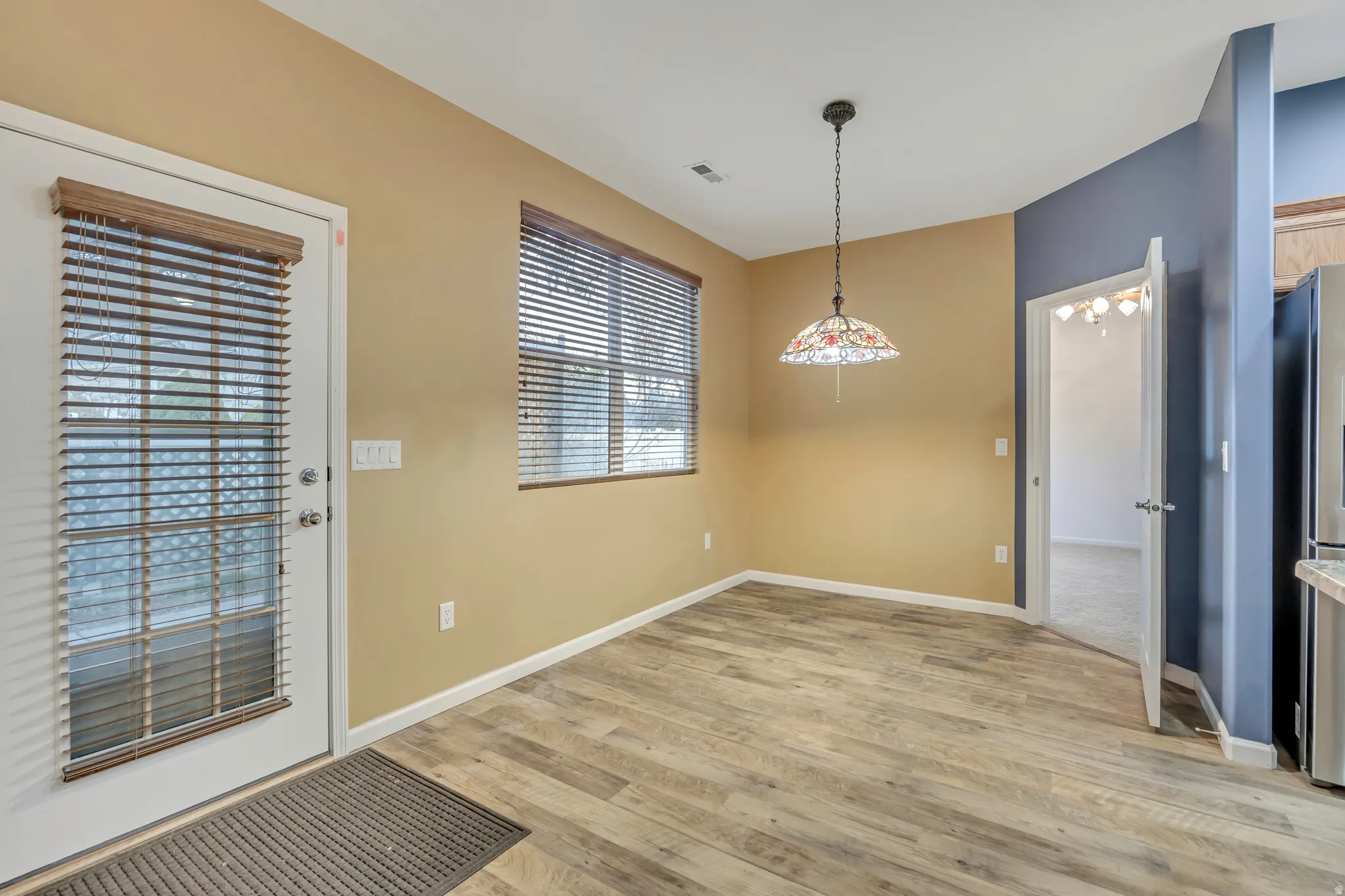 Unfurnished dining area featuring light wood-style flooring and baseboards