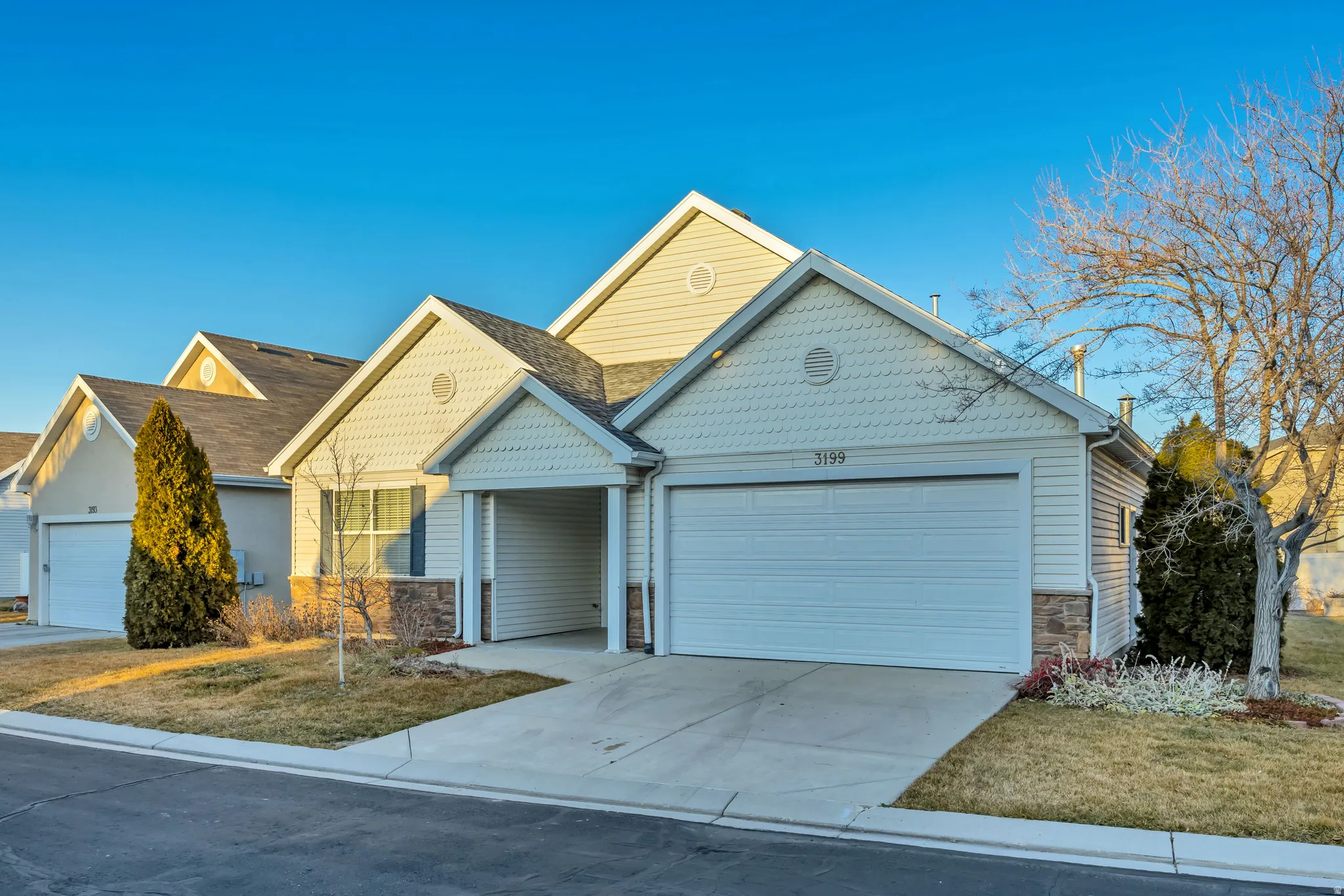 View of front of property with an attached garage, stone siding, driveway, and a front yard
