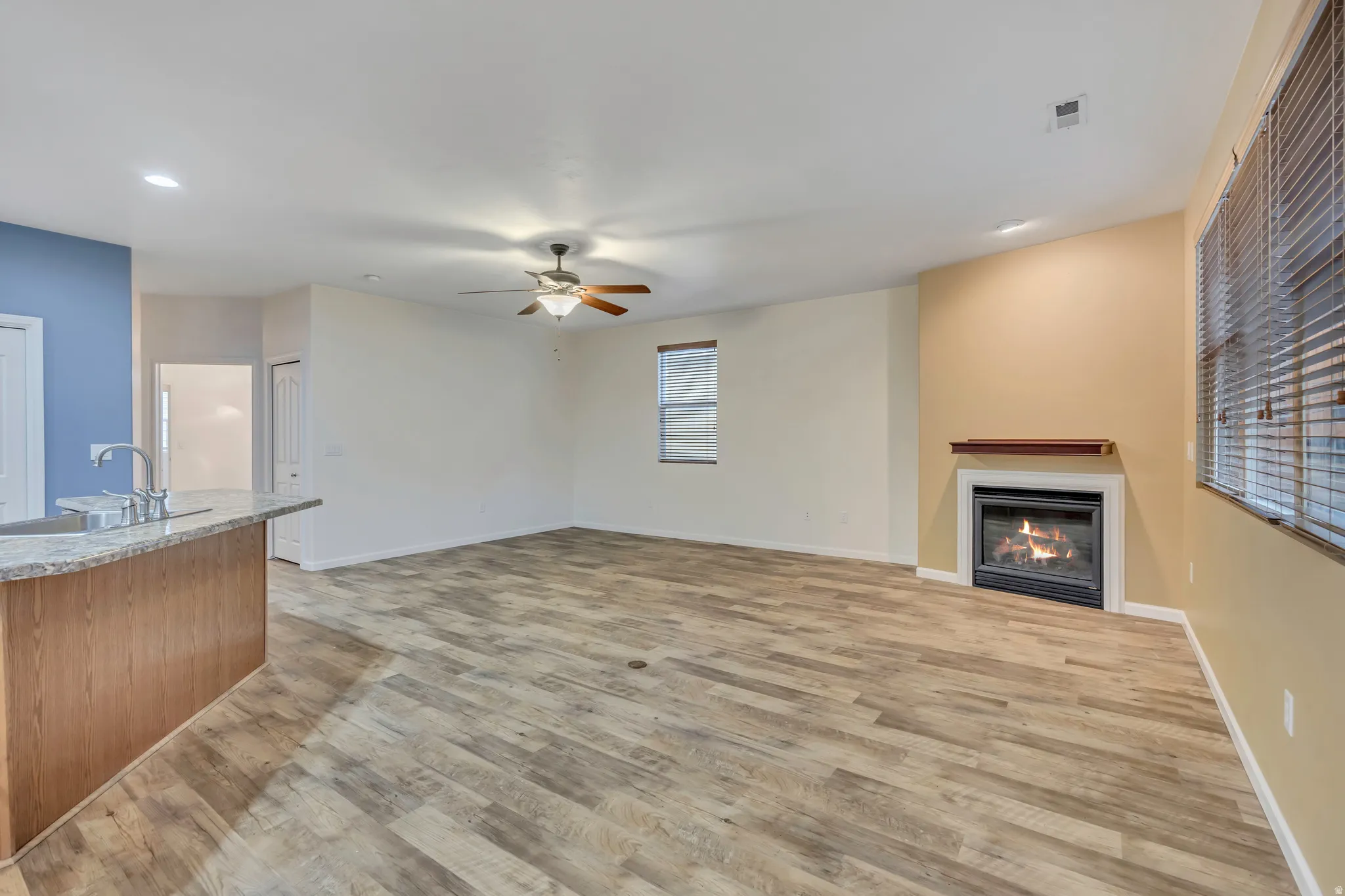 Unfurnished living room with a glass covered fireplace, light wood-style flooring, a ceiling fan, and recessed lighting
