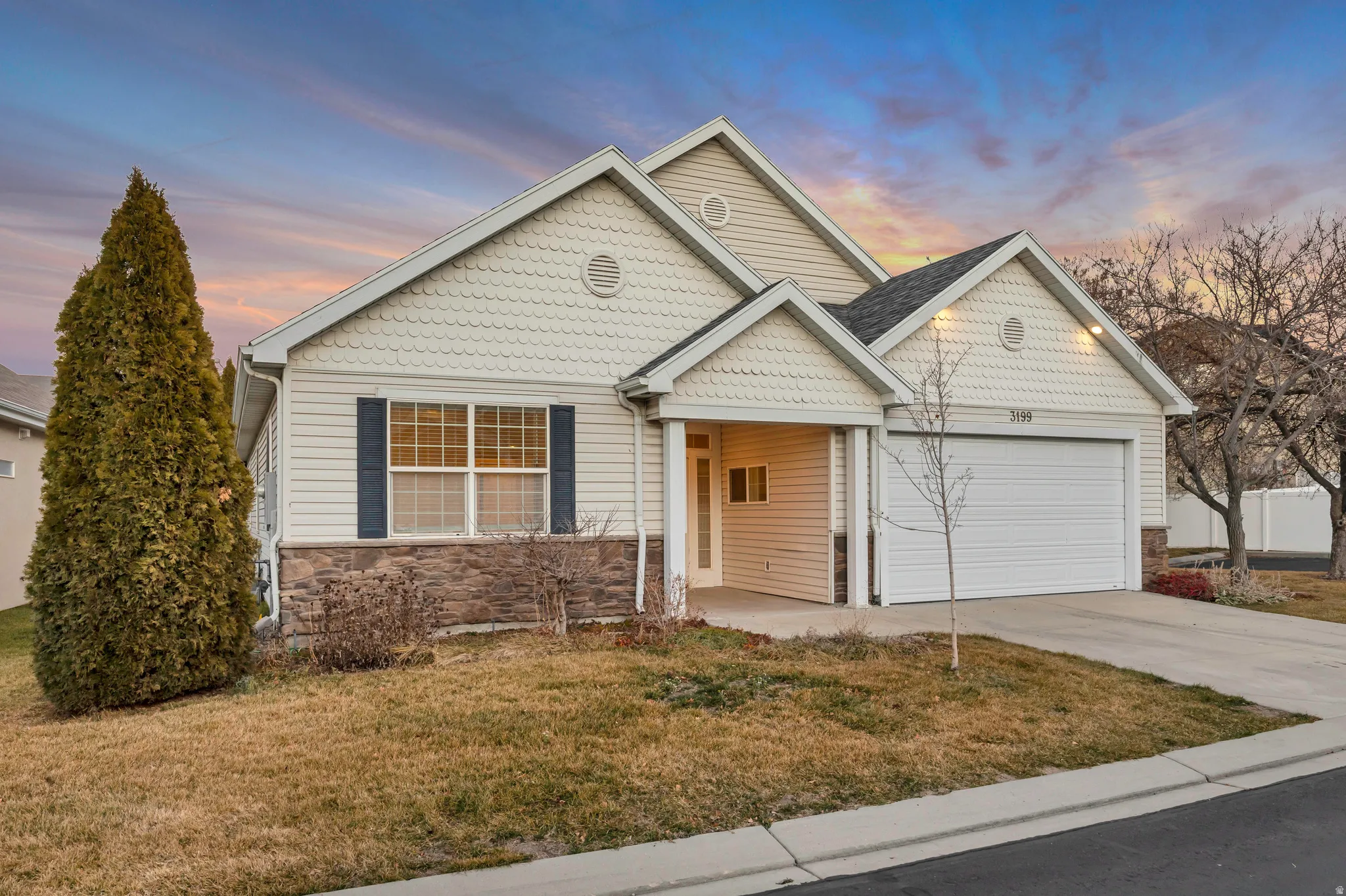 View of front of house with a yard, stone siding, driveway, and an attached garage