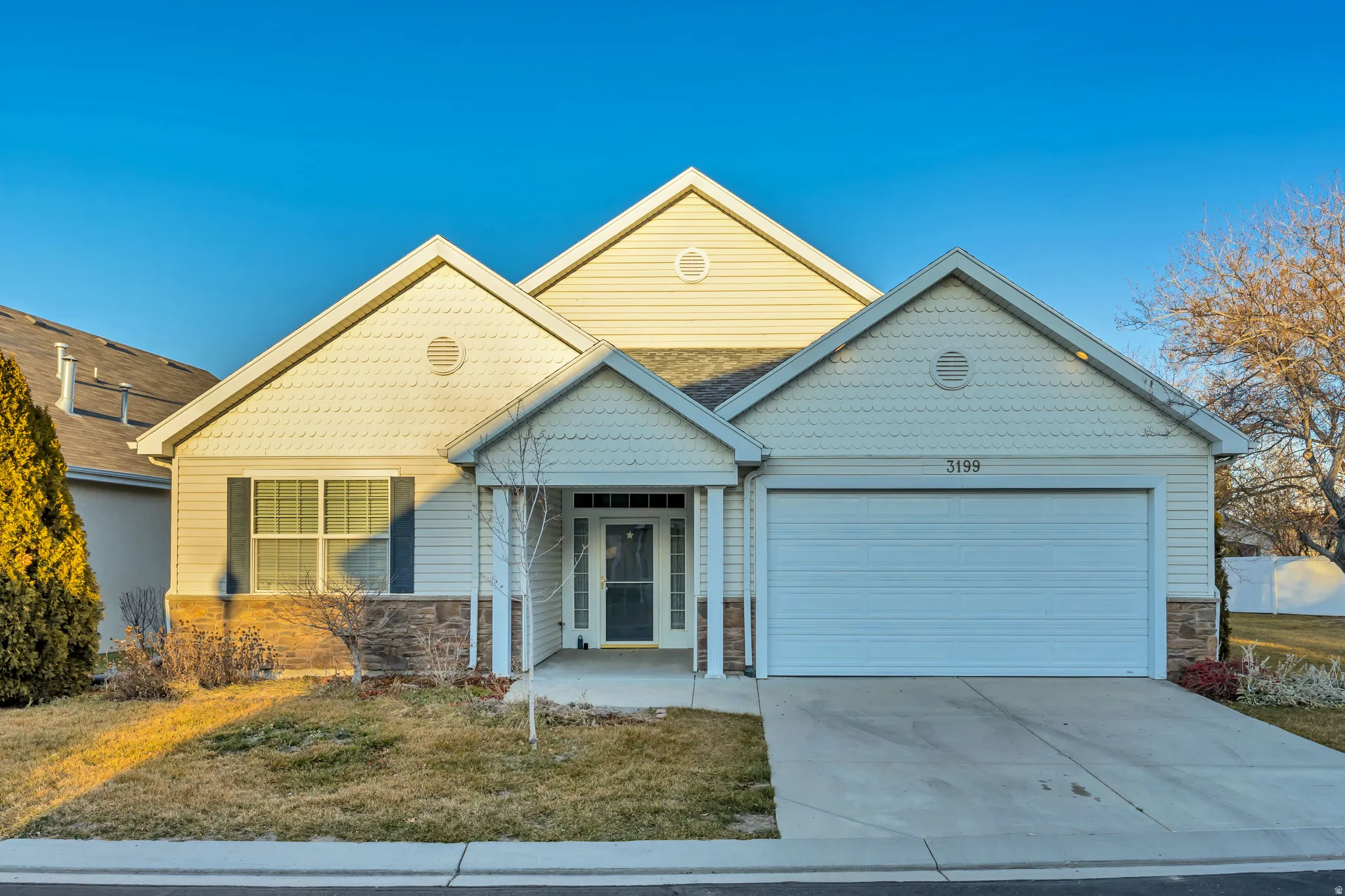 View of front facade featuring stone siding, a garage, driveway, and covered porch