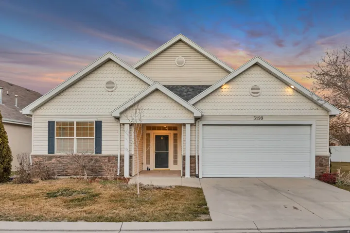 View of front of home with stone siding, concrete driveway, a garage, and a yard