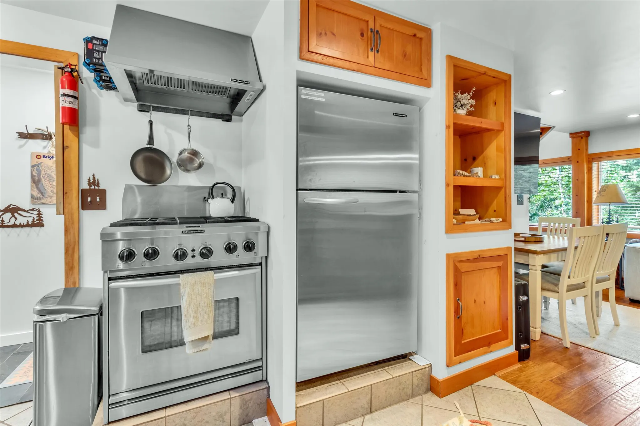 Kitchen featuring a stainless steel range with a professional-grade hood, stainless steel refrigerator, and natural wood cabinetry