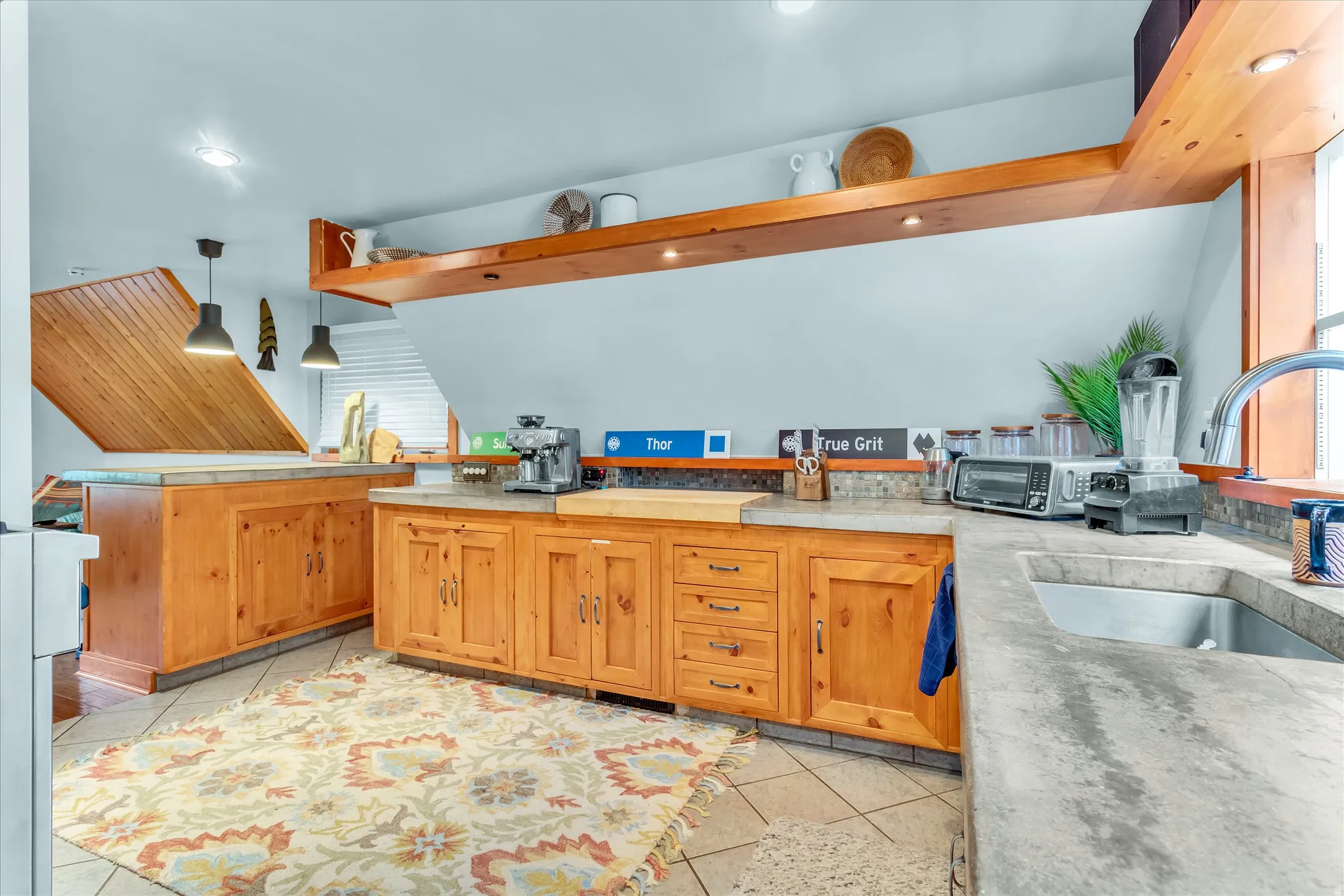 Kitchen featuring wood cabinetry, stone countertops, and a stainless steel sink