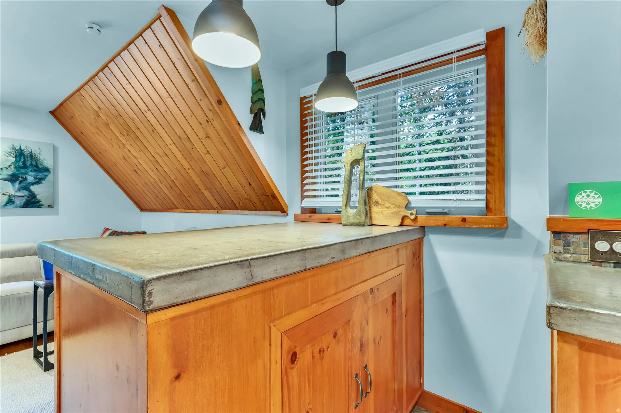 Concrete-finish countertop with natural wood cabinetry and window framing