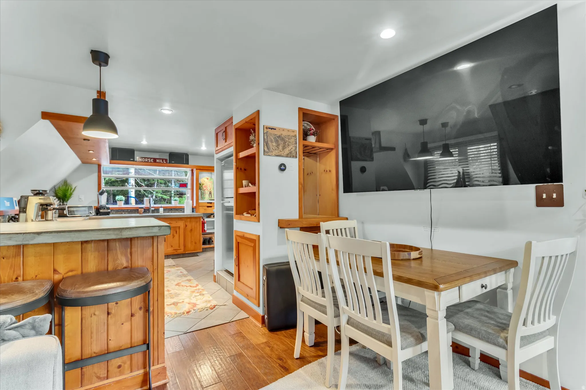 Dining area with wood-finish flooring, a rectangular wood-top table, and built-in shelving
