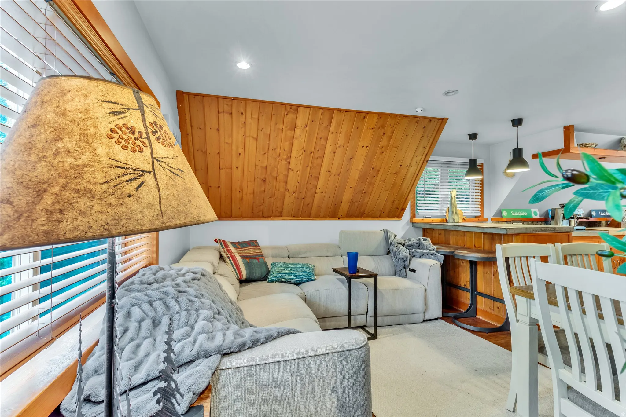 Living area featuring a textured wood-plank accent wall, recessed lighting, and a window with blinds