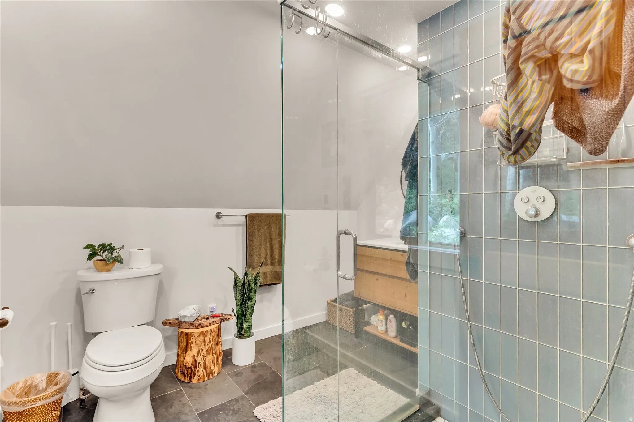 Bathroom featuring a glass-enclosed shower with light blue square tiles and a built-in shower system