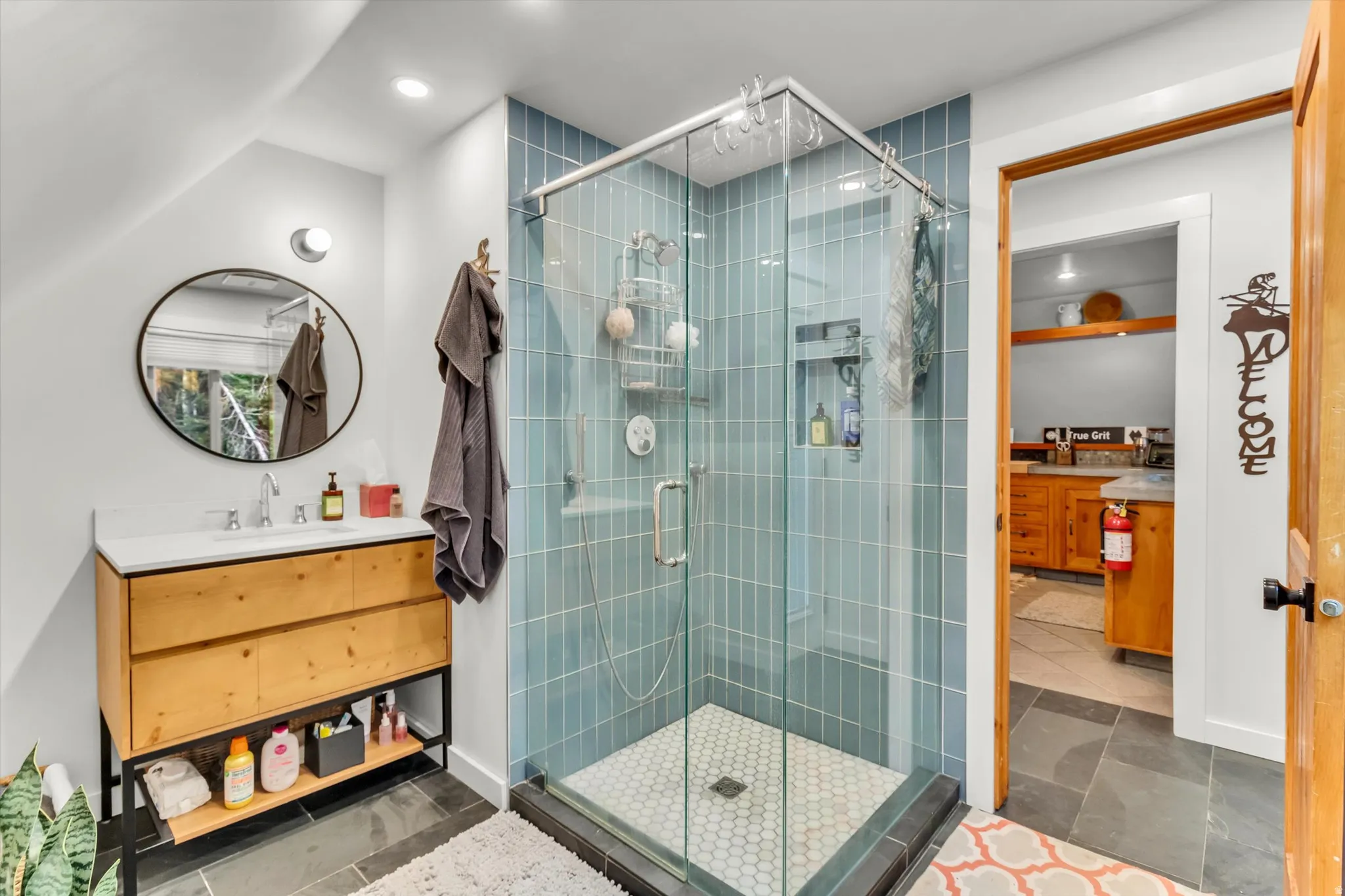 Glass-enclosed shower featuring blue subway tile and a hexagonal tile floor