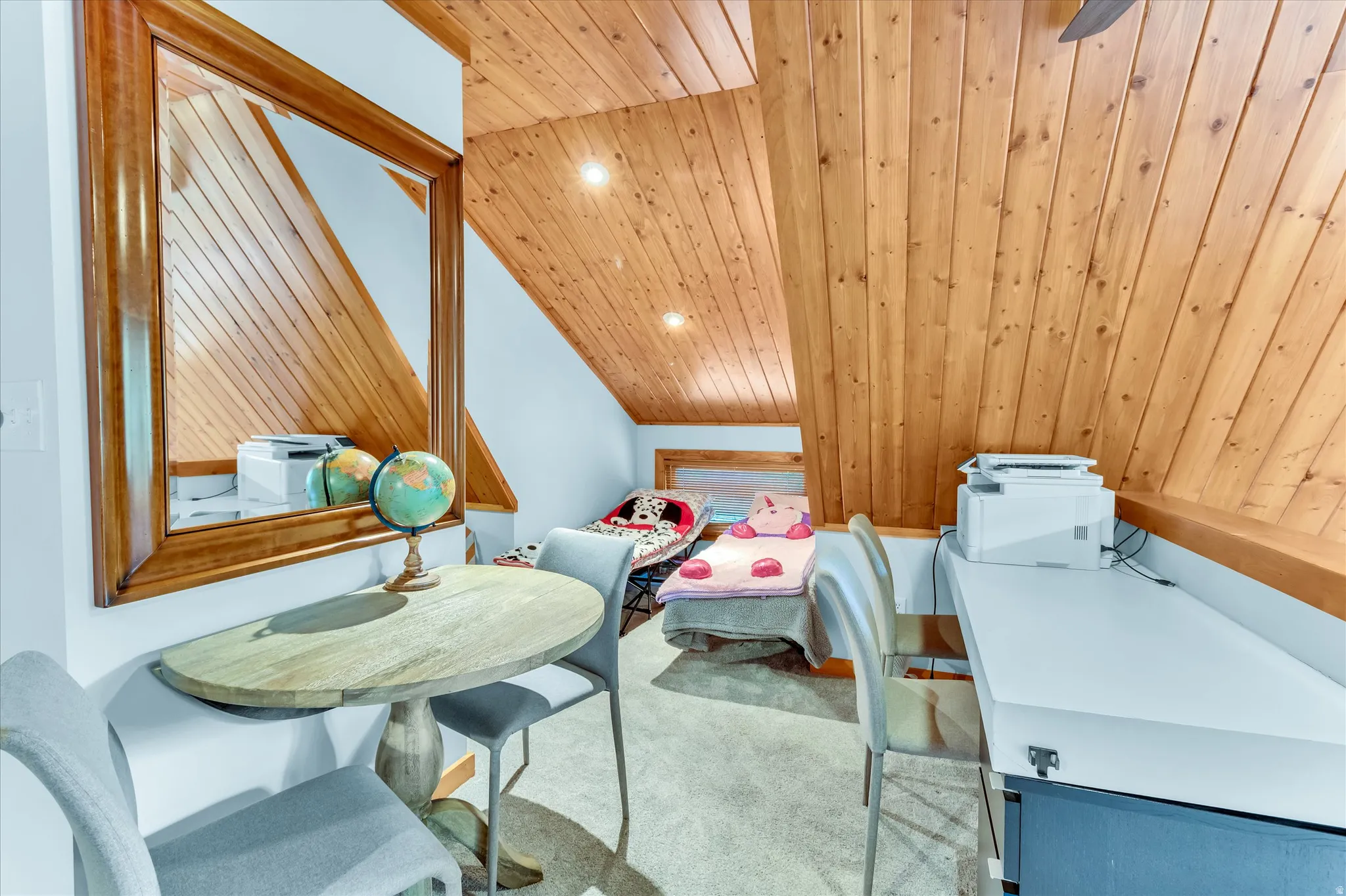 Sloping wood-paneled ceilings with recessed lighting, light gray carpeting, and a built-in desk area