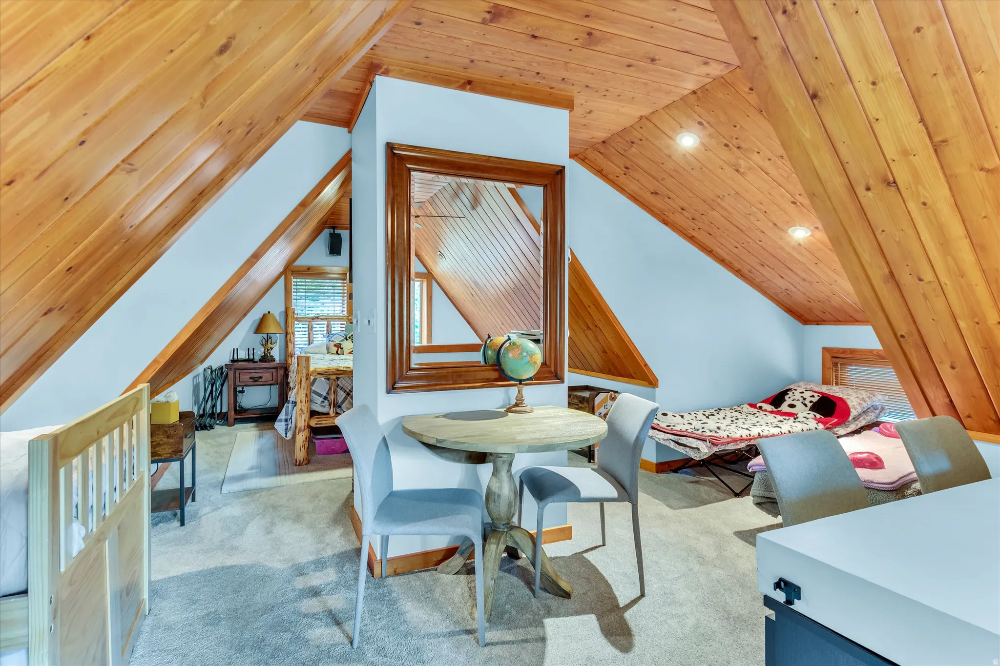 Attic living space featuring wood-paneled ceilings, light blue walls, and a light gray carpeted floor
