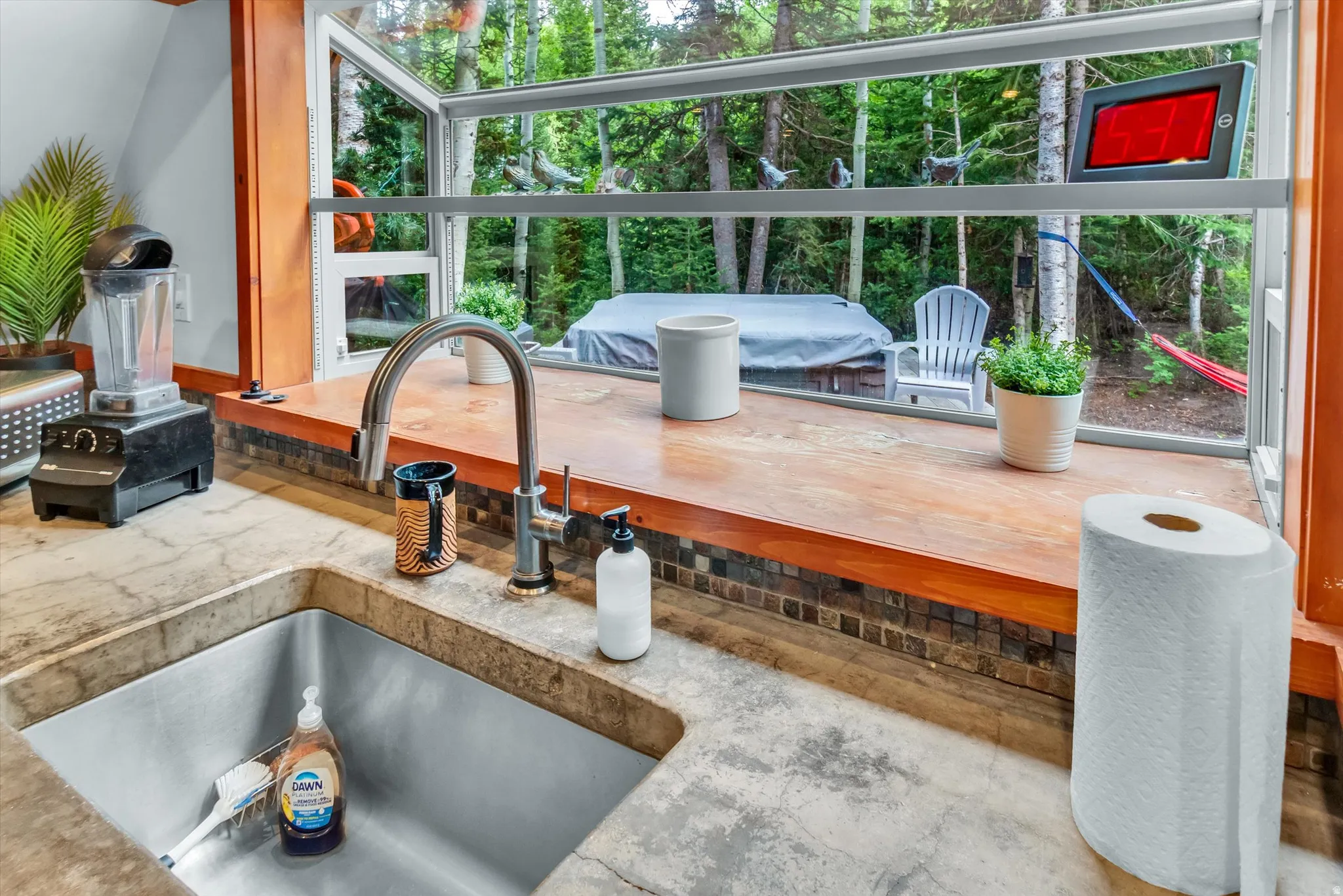 Kitchen featuring a stainless steel sink, gooseneck faucet, and stone-finish countertops