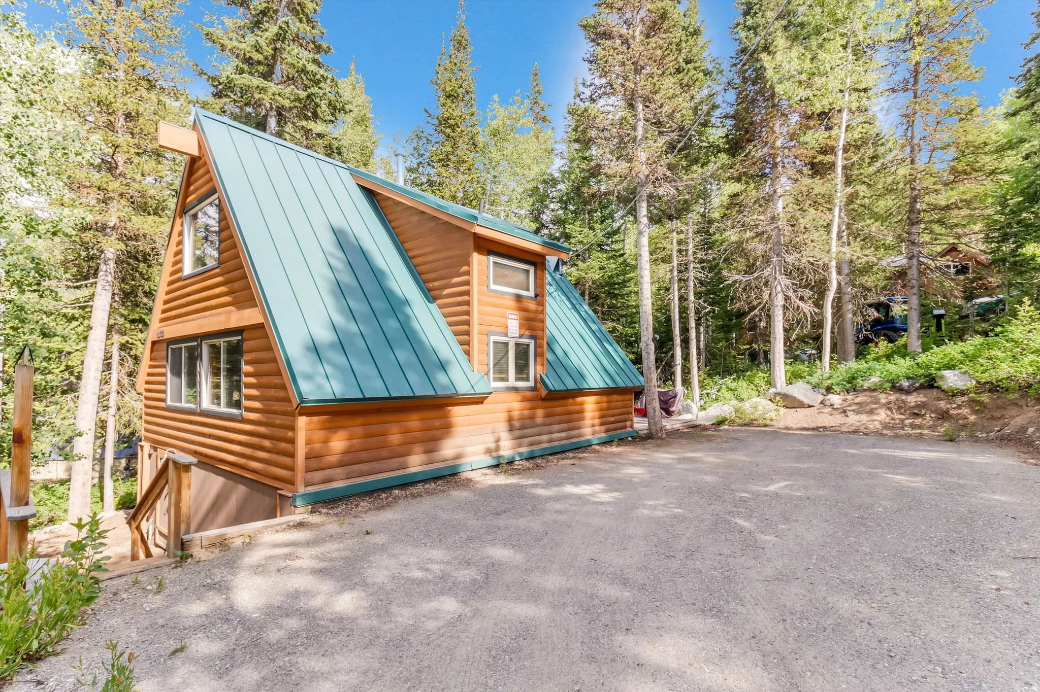 A-frame style residence featuring log-style siding and a prominent teal metal roof