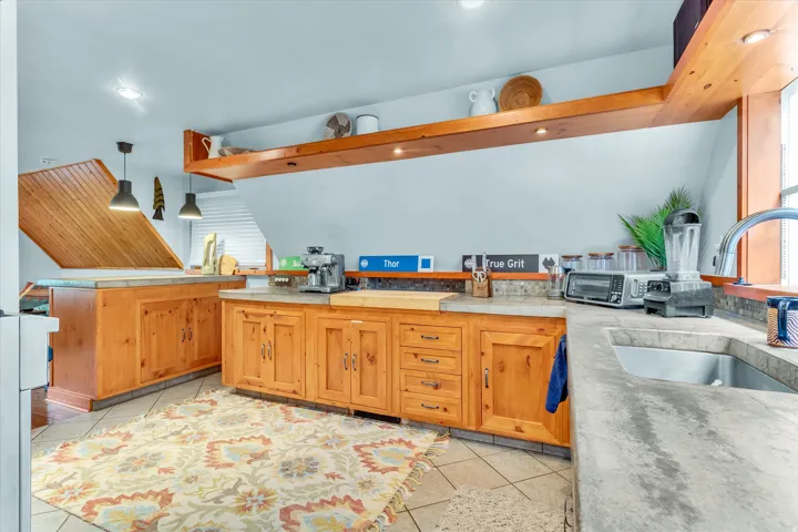 Kitchen featuring wood cabinetry, stone countertops, and a stainless steel sink