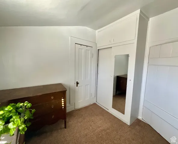 Unfurnished bedroom featuring a closet, carpet flooring, and vaulted ceiling