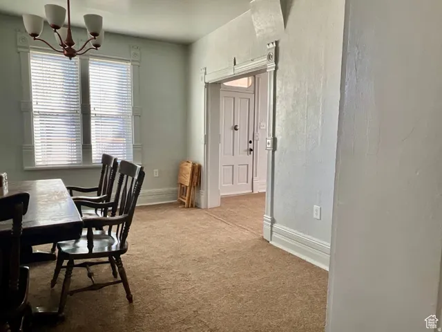 Carpeted dining area with a chandelier and a textured wall