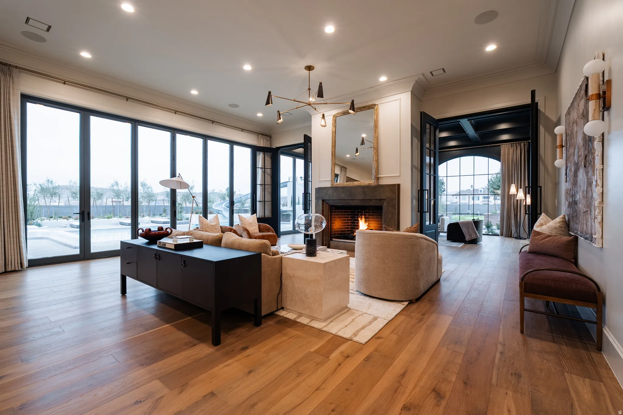 Living area with hardwood / wood-style flooring, a warm lit fireplace, crown molding, and hanging lights