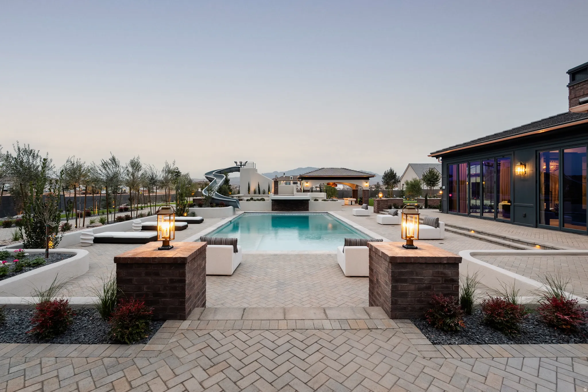 View of pool with a water slide, patio surround, a fenced backyard, and a jacuzzi