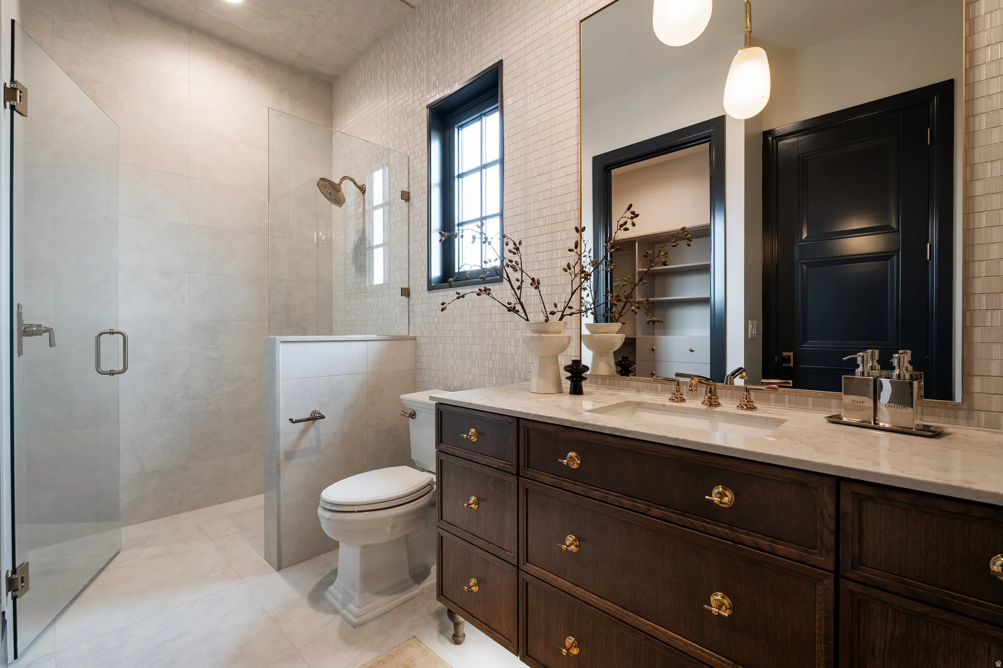 Full bath featuring vanity, a stall shower, tile walls, and light tile patterned floors