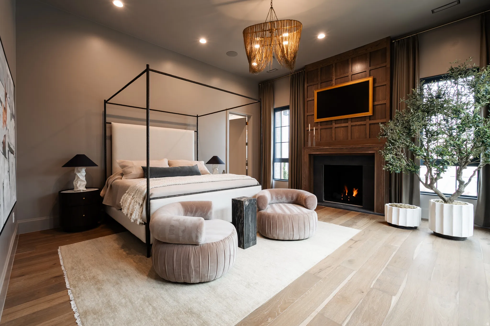 Bedroom featuring wood-type flooring, suspended lighting, and a large fireplace