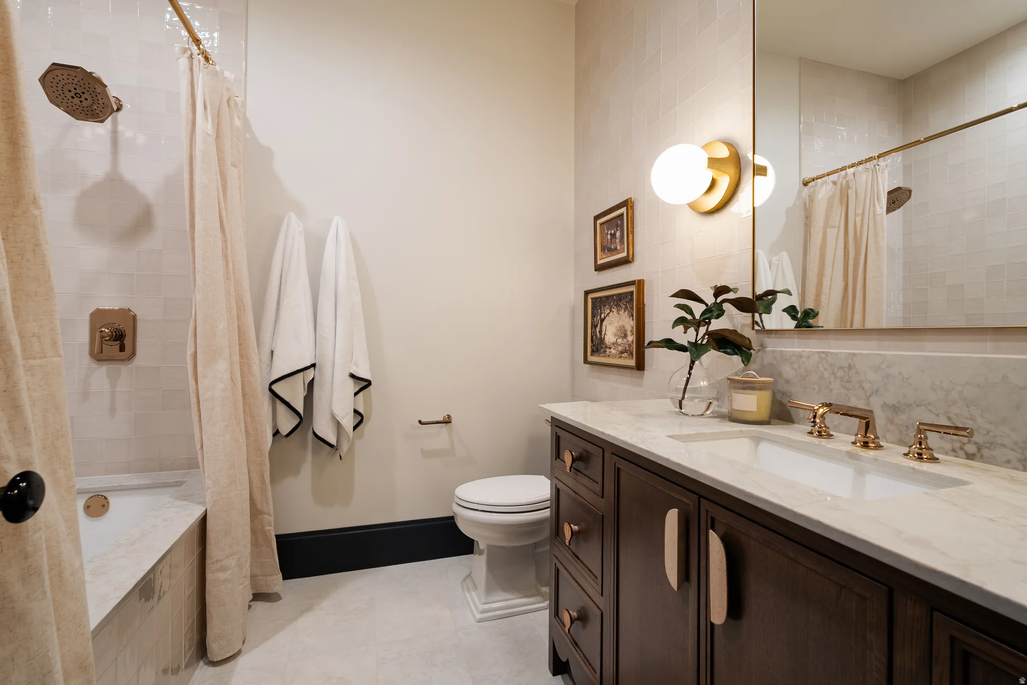 Bathroom featuring vanity, tiled shower / bath combo, and light tile patterned floors