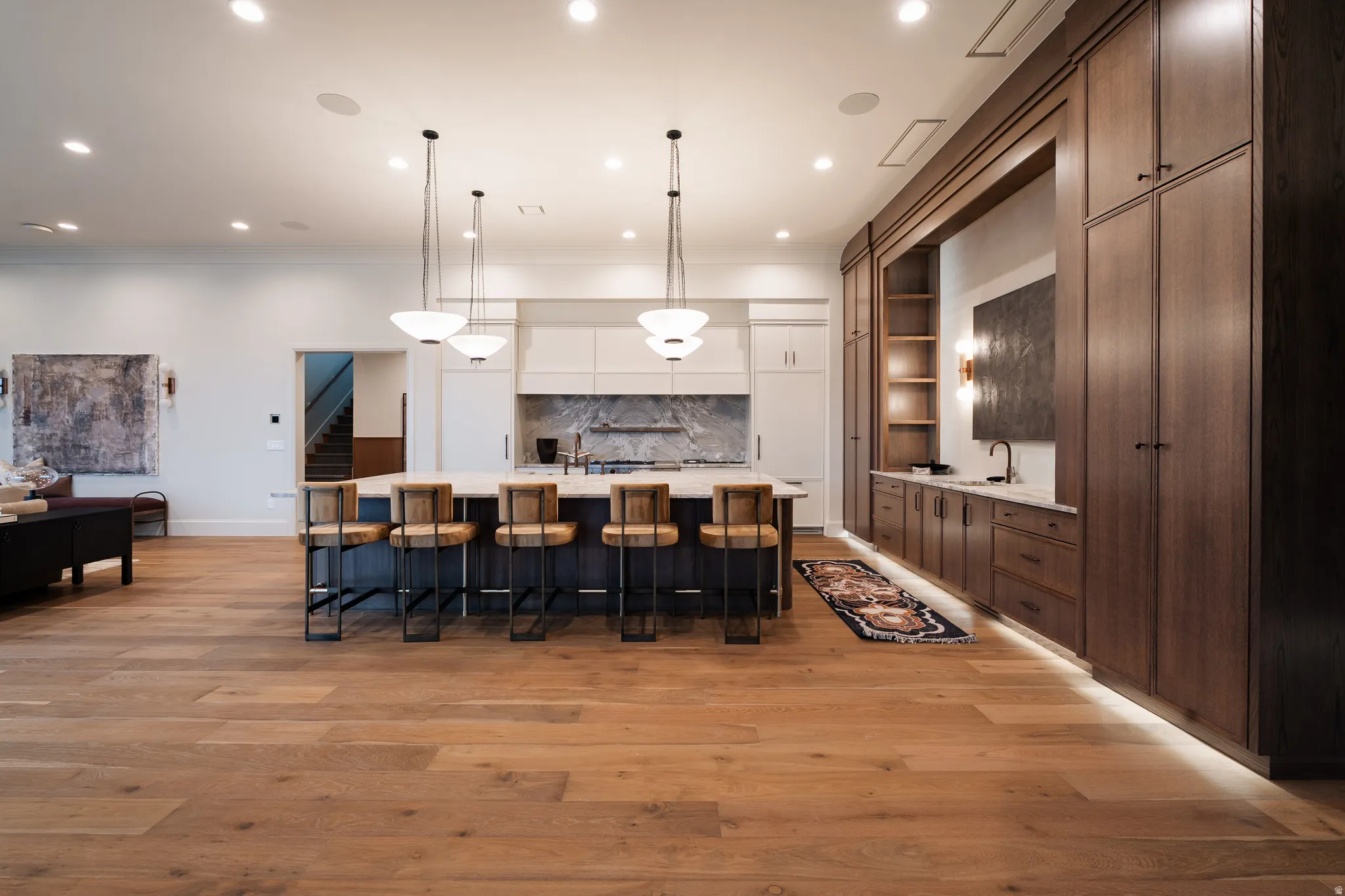 Kitchen with a large island, a kitchen breakfast bar, decorative light fixtures, open shelves, and light wood-style flooring