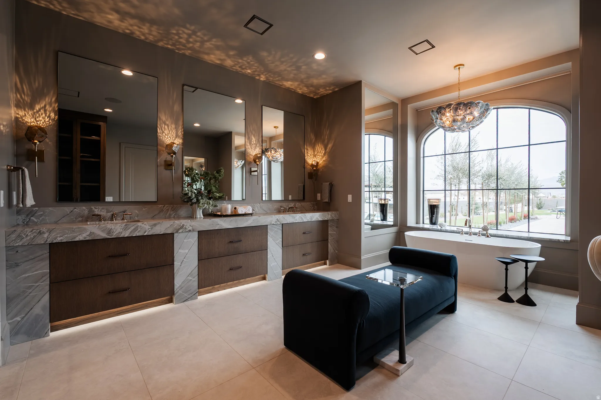 Full bath with double vanity, a chandelier, a freestanding bath, and light tile patterned floors